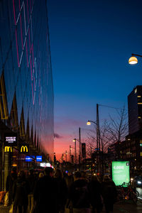 People at illuminated city against clear sky at night