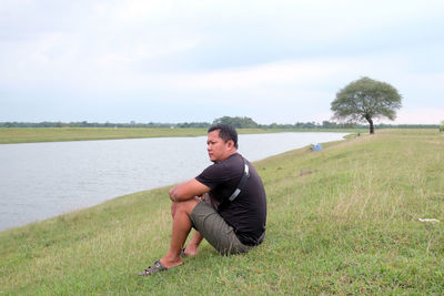 A young indonesian man sitting by the lake