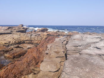 Scenic view of rocks in sea against clear sky