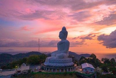 Temple against building during sunset