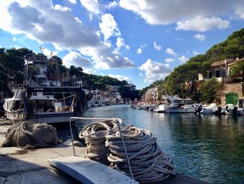 Sailboats moored on harbor by buildings against sky