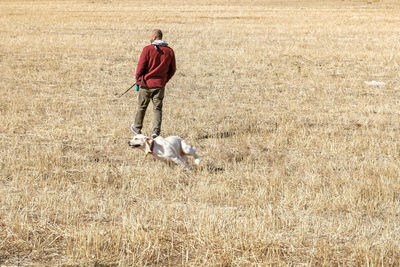 Full length of a man and dog walking on field
