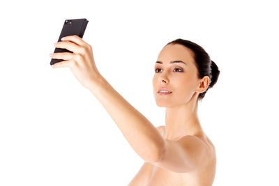 Portrait of woman holding mobile phone against white background