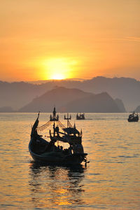 Fishing boat in sea against sky during sunset