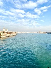 View of city at waterfront against cloudy sky