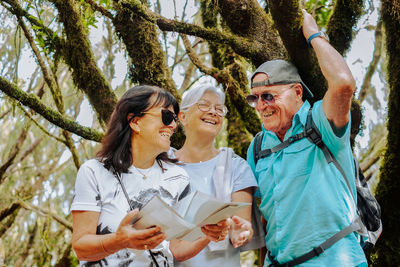 Portrait of female friends standing against trees