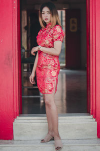 Woman standing by red entrance