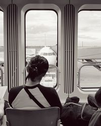 Rear view of man looking through airplane window