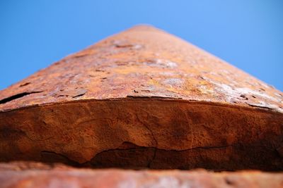 Low angle view of rusty metal against clear blue sky