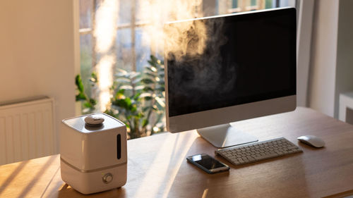 Aroma oil diffuser on the table at home, steam from the air humidifier. increase in air humidity 