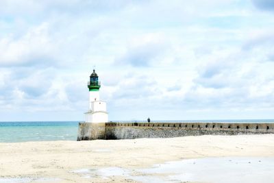 Lighthouse by sea against sky