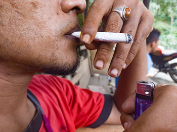 Midsection of man holding cigarette while using smart phone