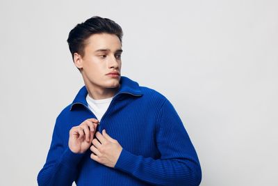 Portrait of young man standing against white background