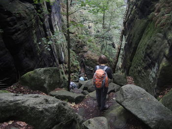 Full length of woman standing on rocks in forest