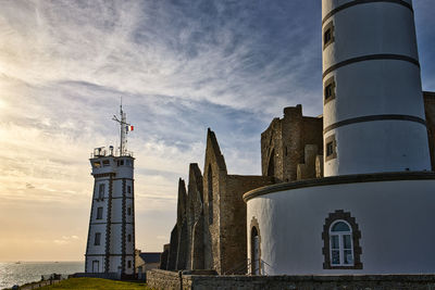 Lighthouse by sea against sky