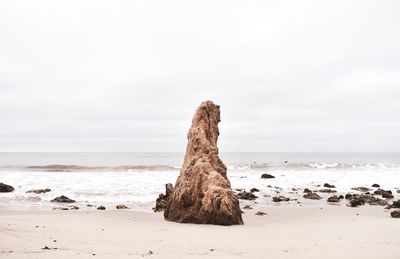 Rock formation on beach against sky