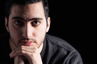 Close-up portrait of young man against black background