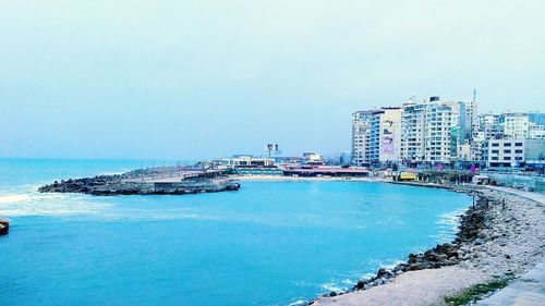 Scenic view of sea by buildings against clear sky
