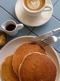 Breakfast with pancake and honey topping, accompany with a cup of cappucino