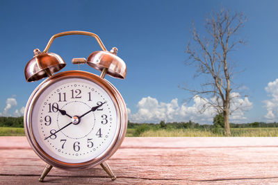 Close-up of clock on table against sky