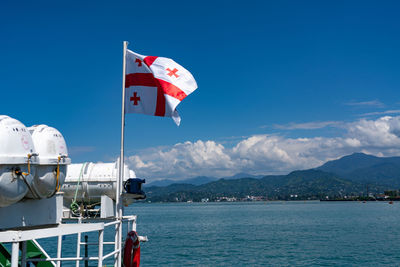 Flag by sea against blue sky