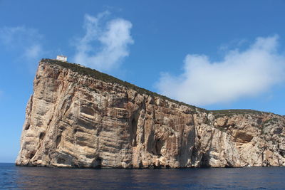 Rock formations by sea against blue sky