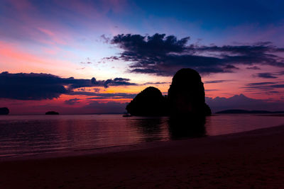 Silhouette rocks on sea against romantic sky at sunset