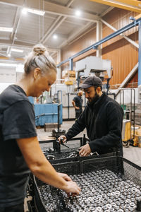 Multiracial female and male employees examining ball bearings in manufacturing factory
