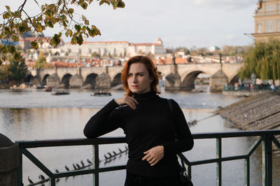 Woman standing by railing against water