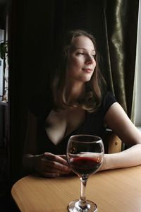 Smiling woman with wineglass on table sitting at restaurant