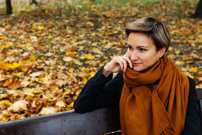 Portrait of a short-haired blonde in a terracotta scarf in an autumn park