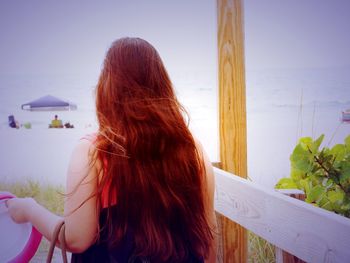 Rear view of redhead woman with long hair at beach