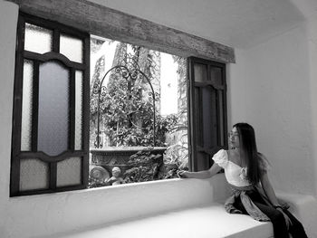 Woman sitting on window of building