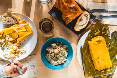 Venezuelan christmas food display on table with traditional hallacas, pan de jamon or ham bread