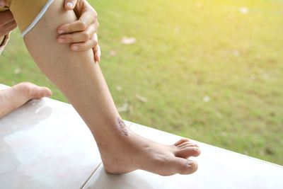 Low section of injured woman sitting on bench outdoors