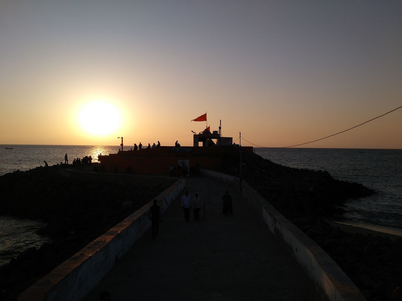 sea, sunset, horizon over water, water, sun, clear sky, beach, silhouette, large group of people, scenics, copy space, orange color, beauty in nature, leisure activity, shore, medium group of people, lifestyles, tranquility, tranquil scene