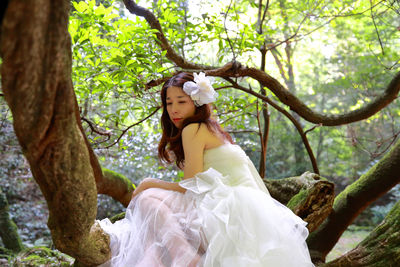 Bride sitting on tree at forest