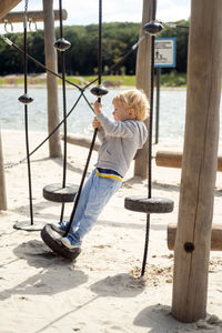 Little caucasian blond boy playing on kids playground in a sunny autumn day