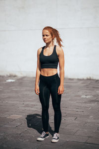 Full length of young woman standing against wall