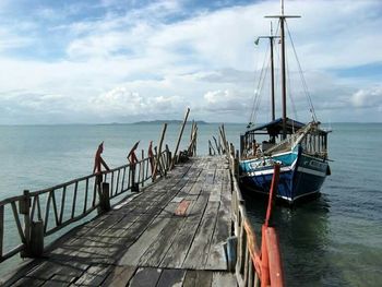 Pier on sea against cloudy sky