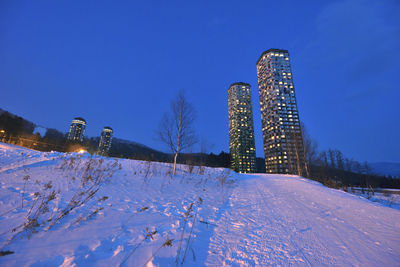 Snow covered field against blue sky at night