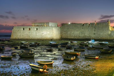 Boats moored in sea against sky during sunset