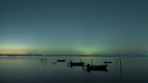 Silhouette boats moored on sea against sky during sunset