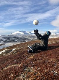 Full length of boy playing with snowball on mountain