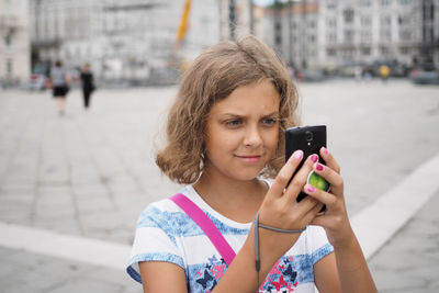 Smiling girl using mobile phone in city