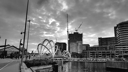 Boats in harbor against cloudy sky