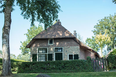 House amidst trees on field against sky