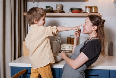 Family fun in the kitchen. mother and son baking carrot cake together. scandinavian kitchen interior