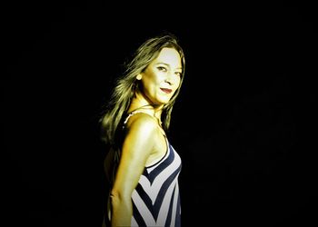 Portrait of a smiling young woman against black background