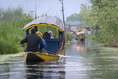 Rear view of people on boat in river during rainy season